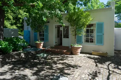 a house with blue shutters and a patio at Auberge Clermont in Franschhoek