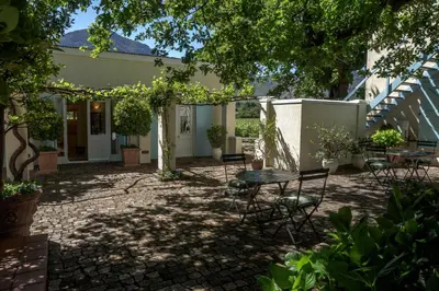 a patio with a table and chairs in a yard at Auberge Clermont in Franschhoek