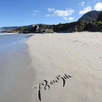 a sign written in the sand on a beach at 78on5th in Hermanus in Hermanus