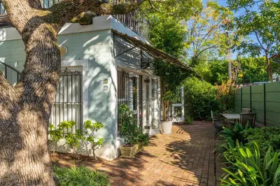 a white house with a tree in front of it at Hedge House Guest House in Cape Town