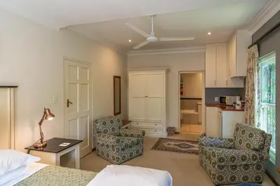 a bedroom with a bed and two chairs and a table at Hedge House Guest House in Cape Town