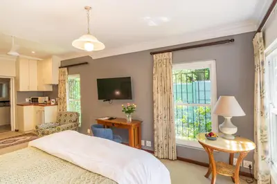 a bedroom with a bed and a table and a window at Hedge House Guest House in Cape Town