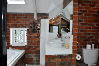 a bathroom with a white sink and a brick wall at Los Olivos at the Yard in Franschhoek
