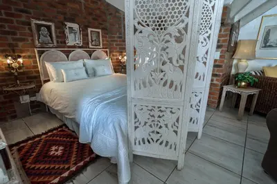 a bedroom with a white bed and a brick wall at Los Olivos at the Yard in Franschhoek
