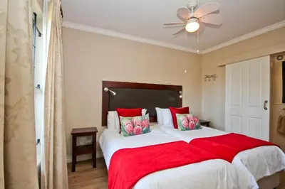 a bedroom with a large bed with a red blanket at Vilaroux in Stellenbosch