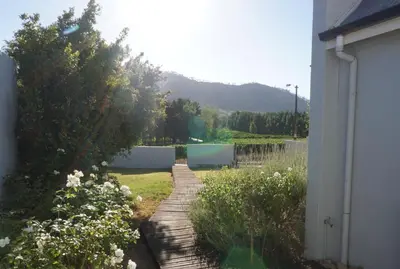 a garden with a wooden walkway next to a house at 5 Pierre Jourdan in Franschhoek