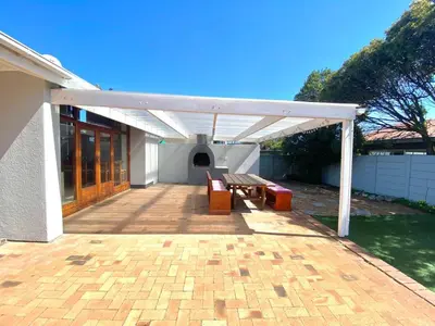 a pavilion with a picnic table and benches on a patio at Villa V in Cape Town