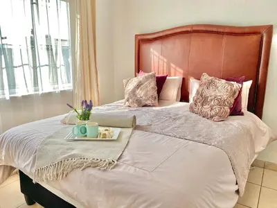a bed with a wooden headboard and a tray of food on it at Villa V in Cape Town