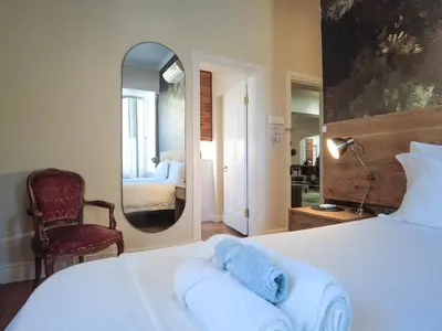 a bedroom with a bed and a mirror and a chair at Laanhof Victorian House Self-Catering in Stellenbosch