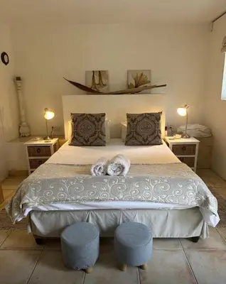 a bedroom with a large bed with two ottomans and pillows at Olive Tree Garden apartment 1 in Cape Town