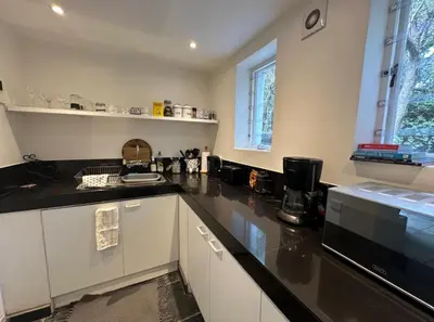a kitchen with white cabinets and black counter tops at Olive Tree Garden apartment 1 in Cape Town
