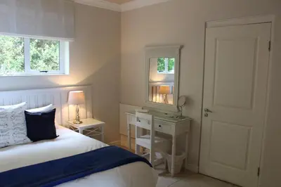 a bedroom with a bed and a desk and a mirror at The Blue Marine Self-Catering in Gordonʼs Bay