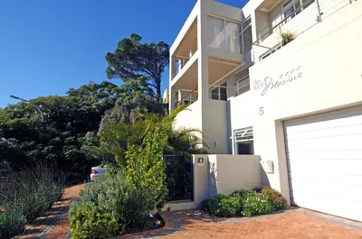 a white house with a gate and a garage at The Blue Marine Self-Catering in Gordonʼs Bay