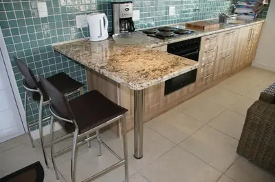 a kitchen with a counter with two stools and a counter top at Freshhh in Bloubergstrand
