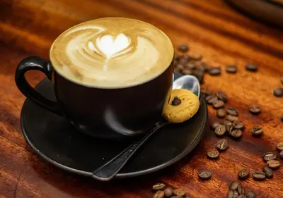 a cup of coffee on a plate with coffee beans at Via's Guesthouse in Greyton