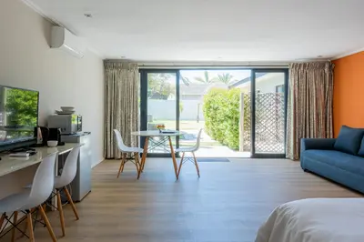 a living room with a blue couch and a table at Bloubergstrandlodge in Bloubergstrand