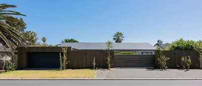 a house with a fence and a garage at Bloubergstrandlodge in Bloubergstrand