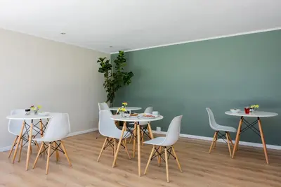 a dining room with white tables and white chairs at Bloubergstrandlodge in Bloubergstrand