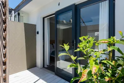 an open glass door on a patio with a plant at Bloubergstrandlodge in Bloubergstrand