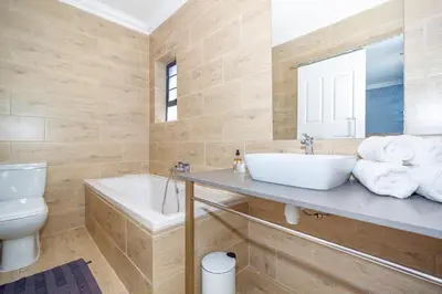 a bathroom with a sink and a toilet and a tub at Bloubergstrandlodge in Bloubergstrand