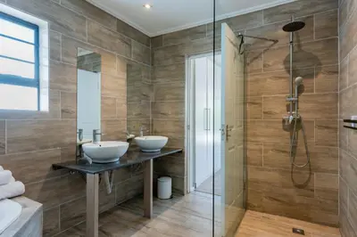 a bathroom with two sinks and a shower at Bloubergstrandlodge in Bloubergstrand
