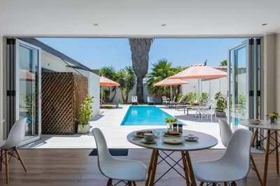 a patio with a table and chairs and a pool at Bloubergstrandlodge in Bloubergstrand