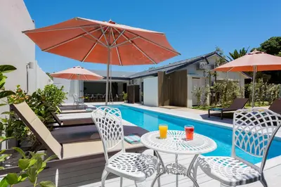 a table and chairs with an umbrella next to a pool at Bloubergstrandlodge in Bloubergstrand