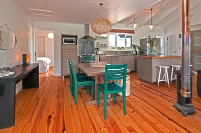 a kitchen with a wooden table and green chairs at Moon River House in Pringle Bay