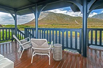 a porch with chairs and a table and a view of the mountains at Moon River House in Pringle Bay