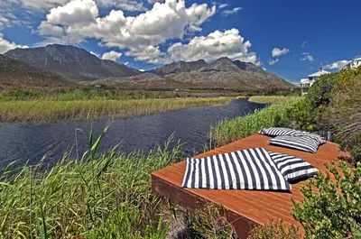 two beds sitting on a wooden deck next to a river at Moon River House in Pringle Bay