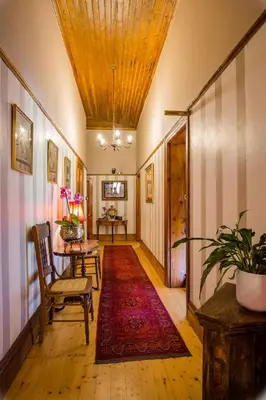 a hallway with a table and chairs and a rug at Roosenwijn Guesthouse in Stellenbosch