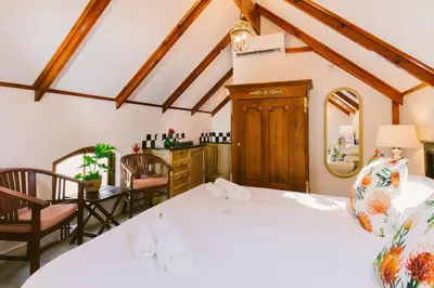 a bedroom with a bed and a table and chairs at Roosenwijn Guesthouse in Stellenbosch
