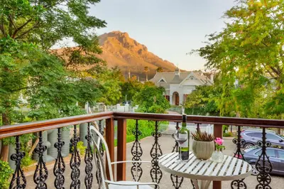 a balcony with a table and chairs and a mountain at Roosenwijn Guesthouse in Stellenbosch