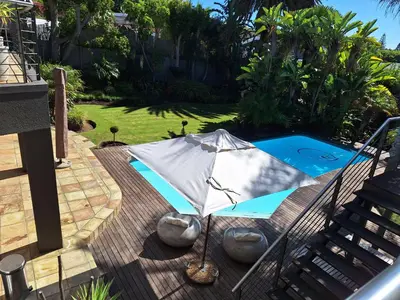 an umbrella sitting on a deck next to a swimming pool at Eversview Guesthouse in Durbanville