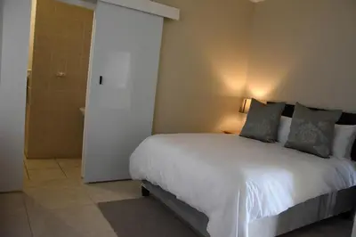 a bedroom with a white bed and a shower at 34onlincoln Guesthouse in Bellville
