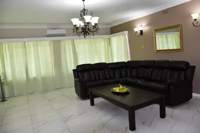 a living room with a black leather couch and a table at 34onlincoln Guesthouse in Bellville