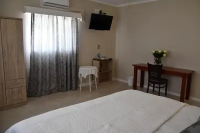a bedroom with a bed and a desk and a table at 34onlincoln Guesthouse in Bellville