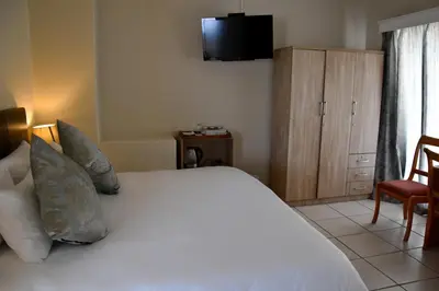 a bedroom with a white bed with a tv on the wall at 34onlincoln Guesthouse in Bellville