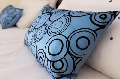 a blue pillow sitting on top of a bed at Acara Guesthouse & Cottages in Stellenbosch