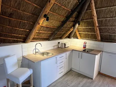a kitchen with white cabinets and a sink and a chair at Acara Guesthouse & Cottages in Stellenbosch