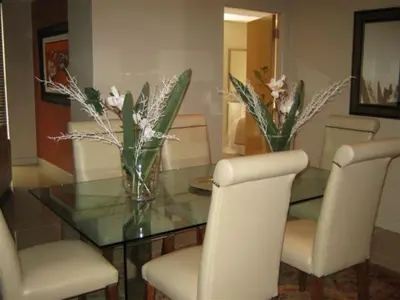a dining room with a glass table with chairs and flowers at Hibernian Towers 1802 Self Catering Accommodation Strand Western Cape South Africa in Strand