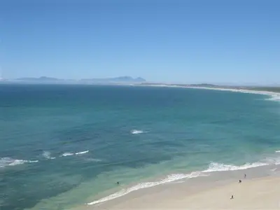 an aerial view of a beach with people in the ocean at Hibernian Towers 1802 Self Catering Accommodation Strand Western Cape South Africa in Strand