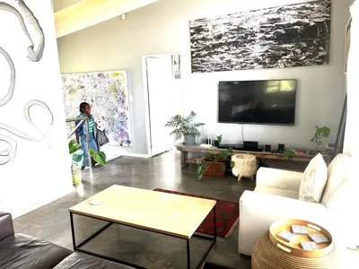 a woman standing in a living room with a tv at 3 Indigo with Solar in Hermanus