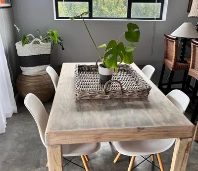a wooden table with white chairs and plants on it at 3 Indigo with Solar in Hermanus