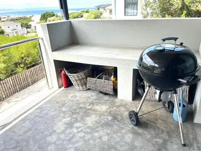 a grill sitting next to a bench on a balcony at 3 Indigo with Solar in Hermanus