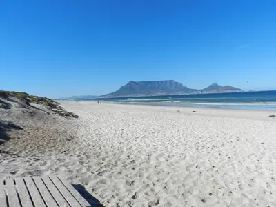 a white sandy beach with mountains in the background at Sunset at Diluta in Cape Town