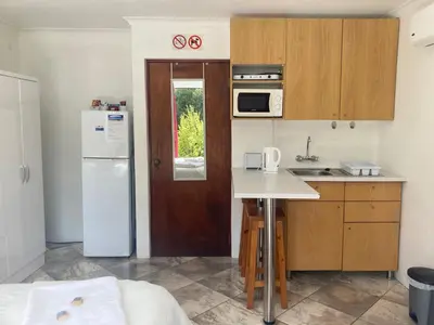 a small kitchen with a white refrigerator and a sink at Suikerbekkie in Somerset West