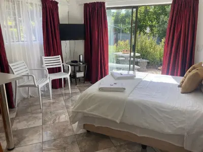 a bedroom with a large bed and a table and chairs at Suikerbekkie in Somerset West