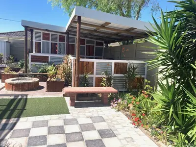 a garden with a bench and a house at Arum Field Accommodation in Table View