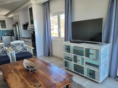 a living room with a television and a wooden table at 109 da Gama on Beach in Strand